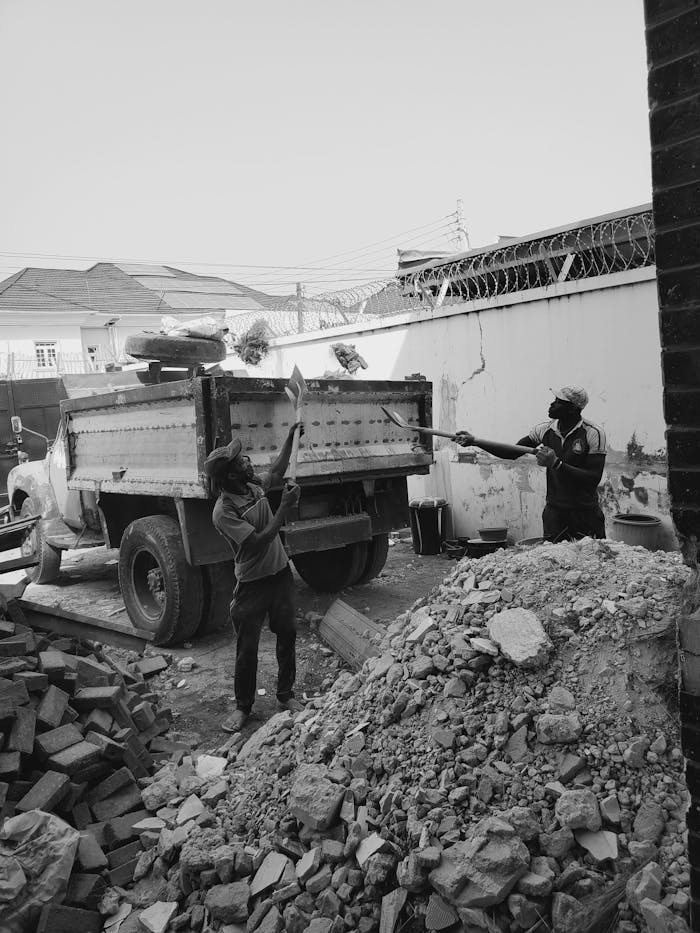 Two construction workers loading debris onto a truck at a worksite in Lekki, Nigeria.